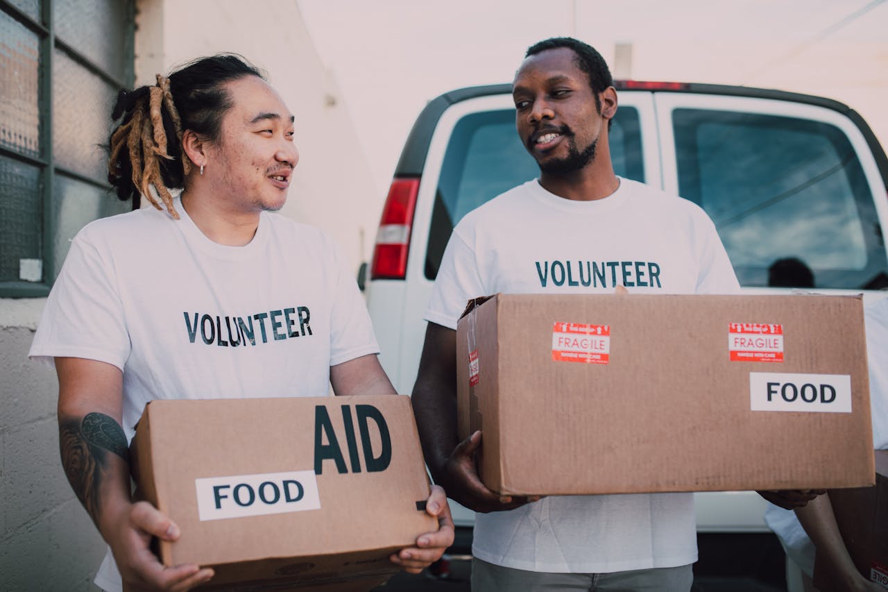 services-03 Two volunteers distributing food aid boxes for community relief outdoors.