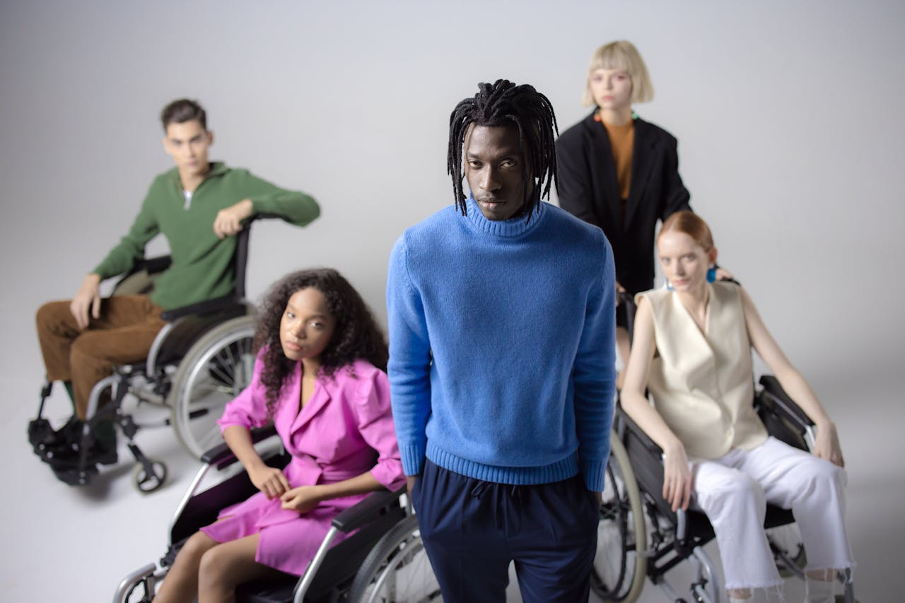 Diverse group of people including individuals in wheelchairs, studio setting, white background.
