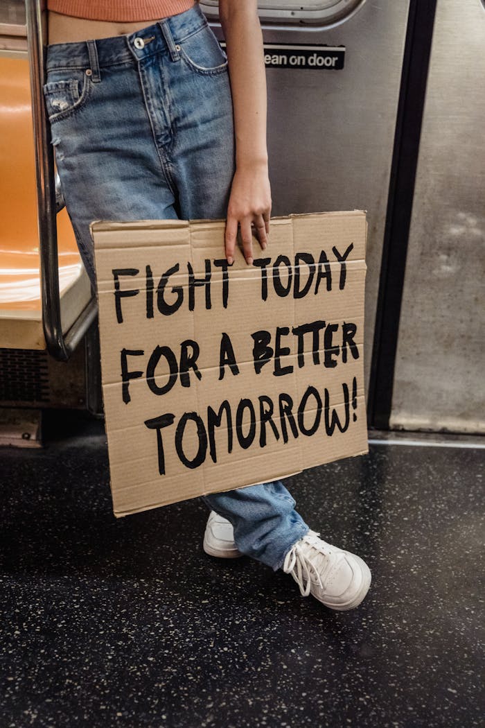 services-01 A person holding a protest sign in a subway advocating for a better future.